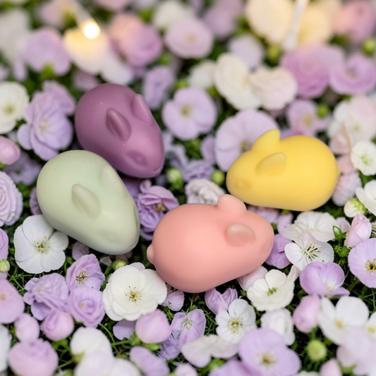 Four small animal figurines (pig, duck, rabbit, and bear) on a bed of flowers.